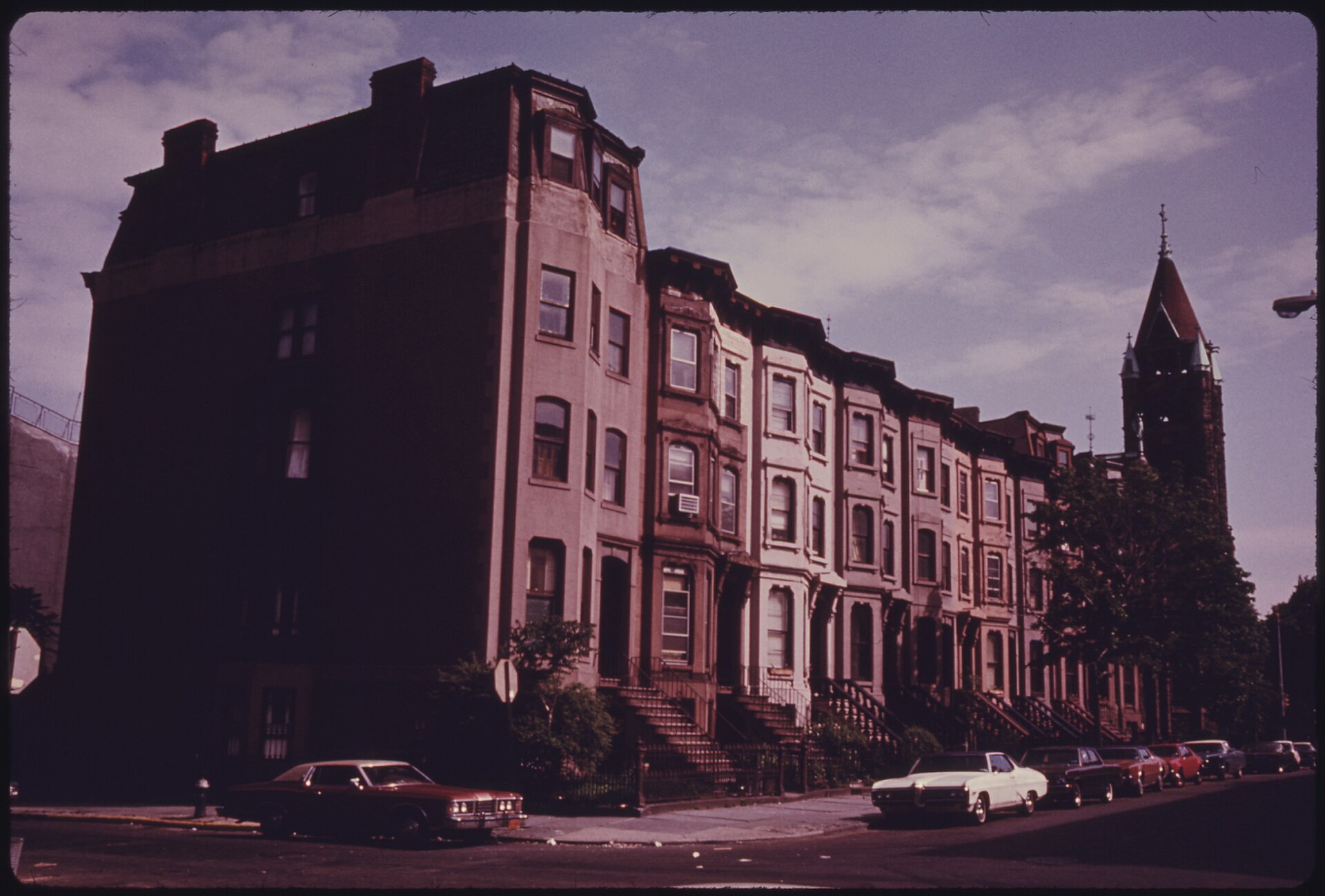 A row of brownstones in Park Slope with cars parked along the kerb
